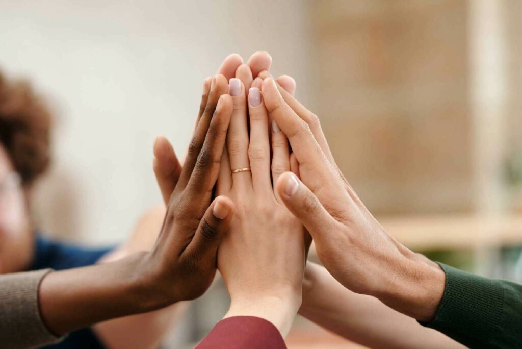 Optimizaci&oacute;n de los recursos humanos, con una imagen de un equipo chocando las manos