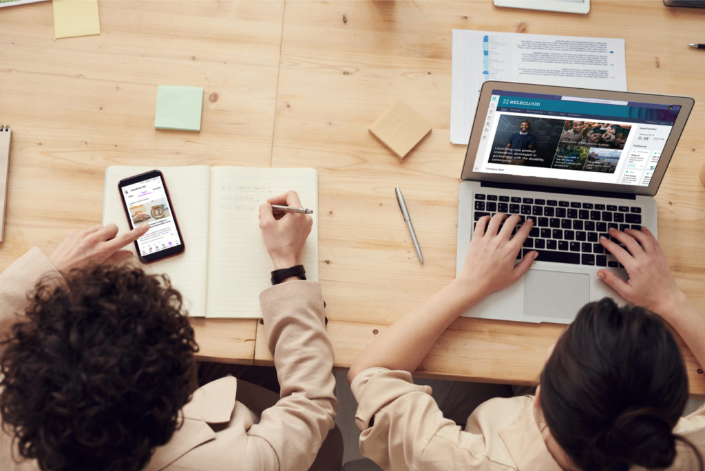 Dos personas revisan la intranet en Teams desde un port&aacute;til y desde el m&oacute;vil