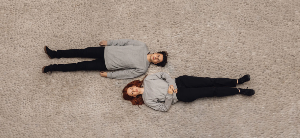 Imagen promocional de Minimalism, marca de productos sostenibles, que muestra a dos chicos con ropas de colores neutros tumbados en el suelo